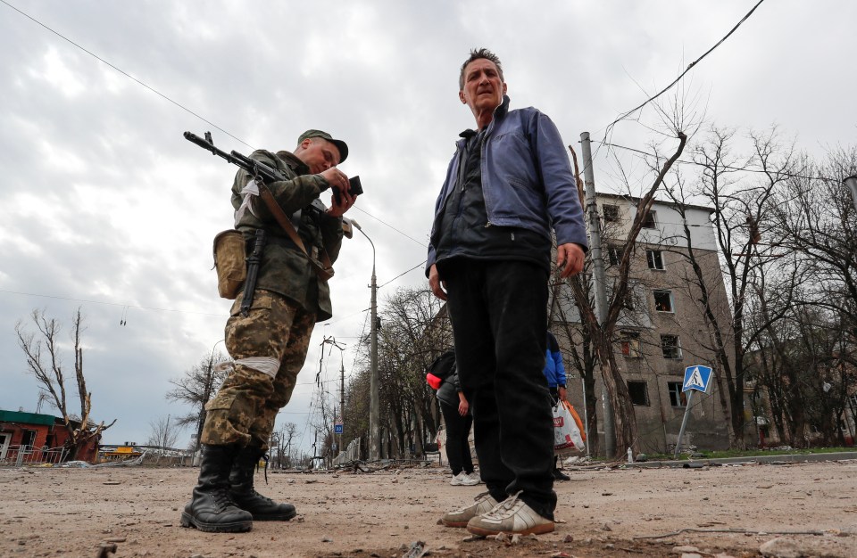 A service member of pro-Russian troops checks documents of a civilian in Mariupol