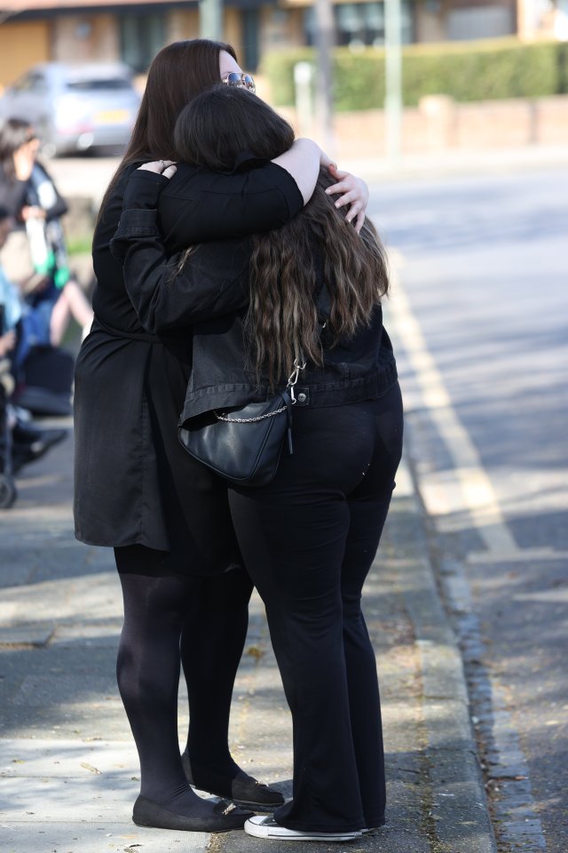 Two fans embrace as they wait to pay their respects