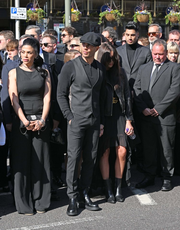 Max George looks solemn as he watches the procession