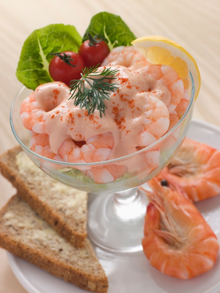 a bowl of shrimp salad with tomatoes and lemon slices