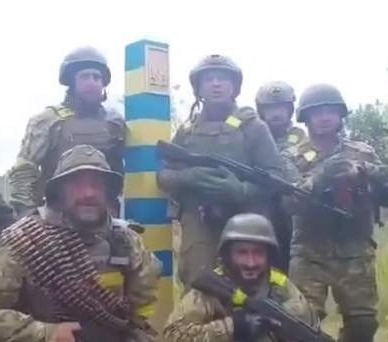 Ukrainian forces pose near a border post after they pushed Putin's troops back into Russia