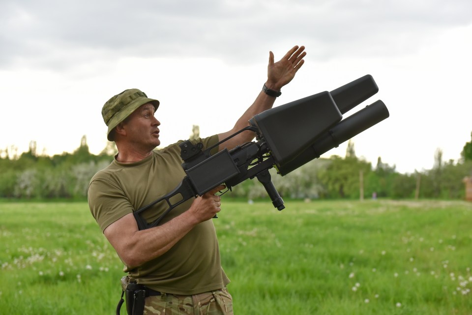 A Ukrainian soldier showcases an anti-drone weapon in Kyiv