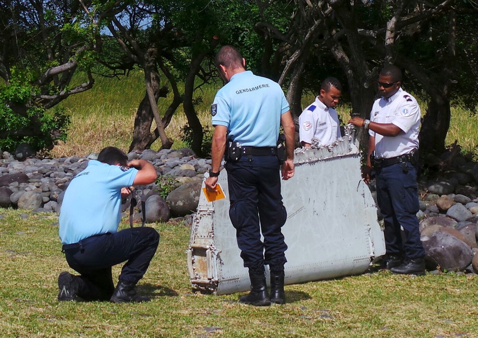 Cops inspect a large piece of plane debris which was found on the beach