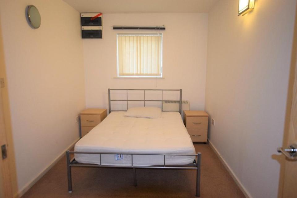 This bedroom looks like a cell with bare furniture and one tiny window