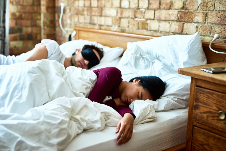 Couple sleeping in a hotel bed.