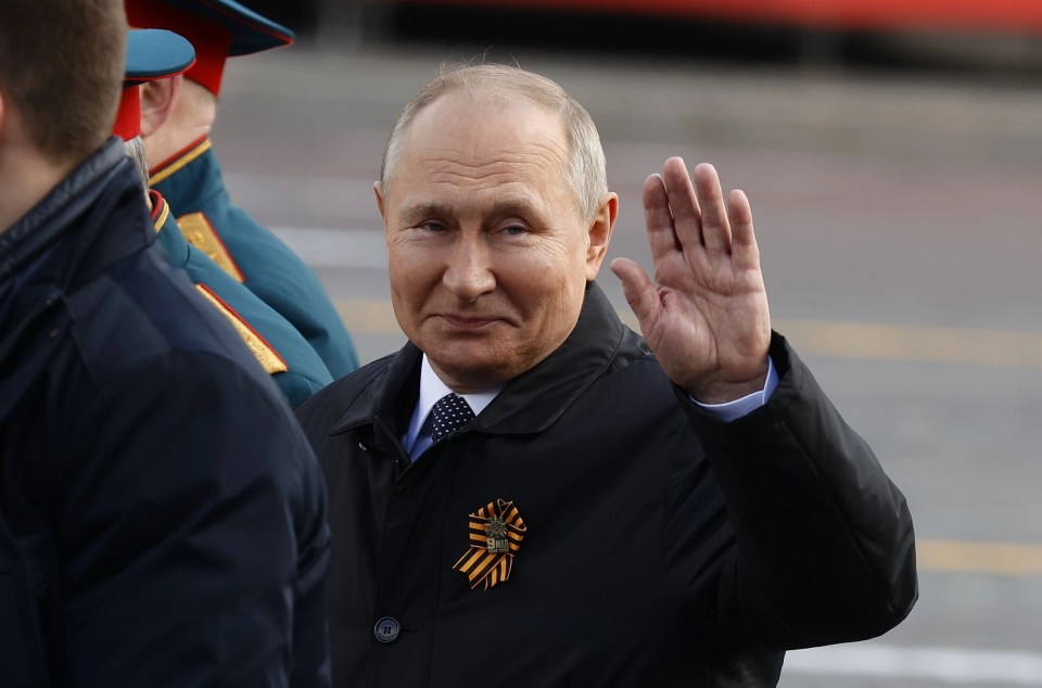 Vladimir Putin waves as he appears during the Victory Day parade in Moscow