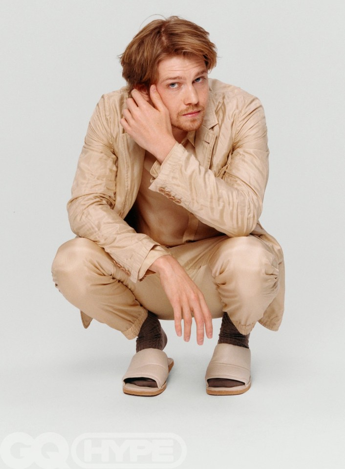 Joe Alwyn is pictured wearing a beige suit and pool sliders in the new edition of GQ Hype magazine