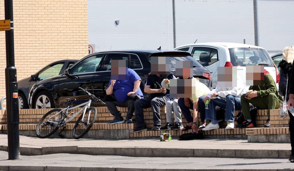 Locals sitting on a wall drinking cans of Strongbow at midday