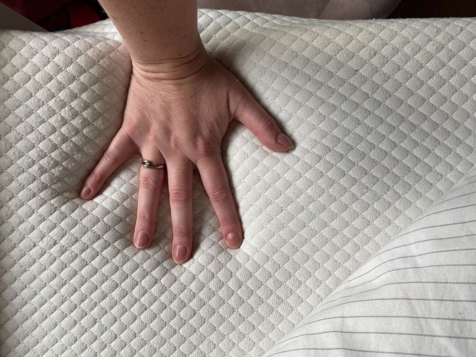 a woman 's hand is on a white quilted fabric