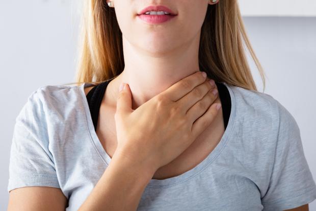 a woman in a blue shirt is holding her chest