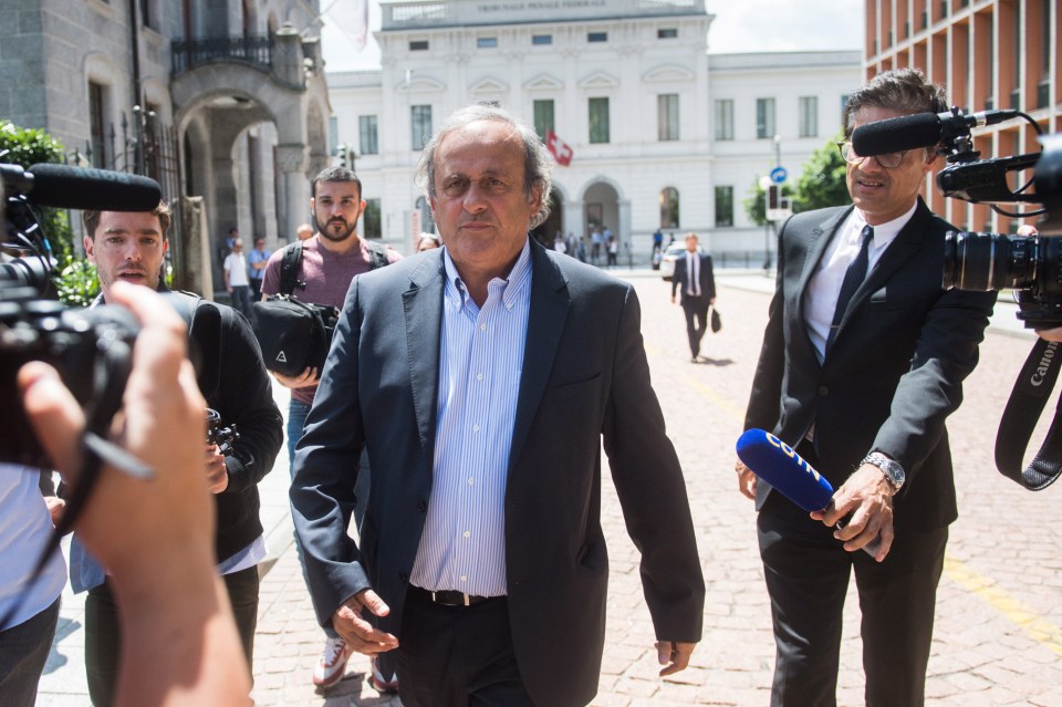 Michel Platini (centre) is surrounded by journalists as he leaves court after the first day of his trial