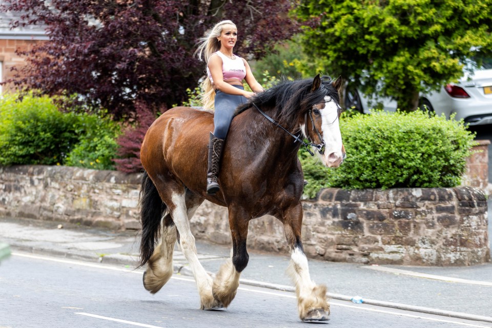 A woman rides her horse through the street on the first day of the Appleby Horse Fair