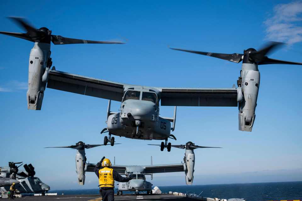 Aviation Boatswains Mate signals to the pilots of the MV-22 Osprey assault support aircraft as it departs off the flight deck of an assault ship