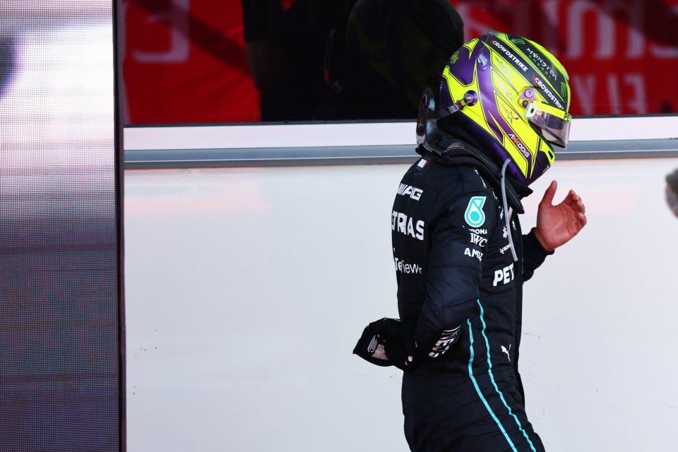 The Brit holds his back as he walks to Mercedes' team garage