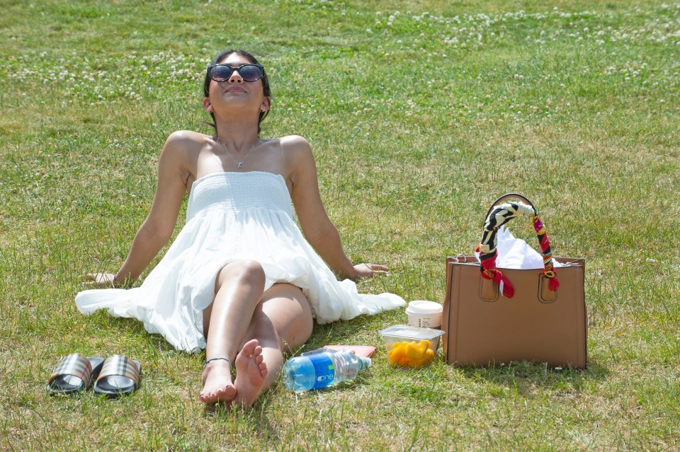 A young woman soaks up the rays in Greenwich Park as temperatures soared to 32C