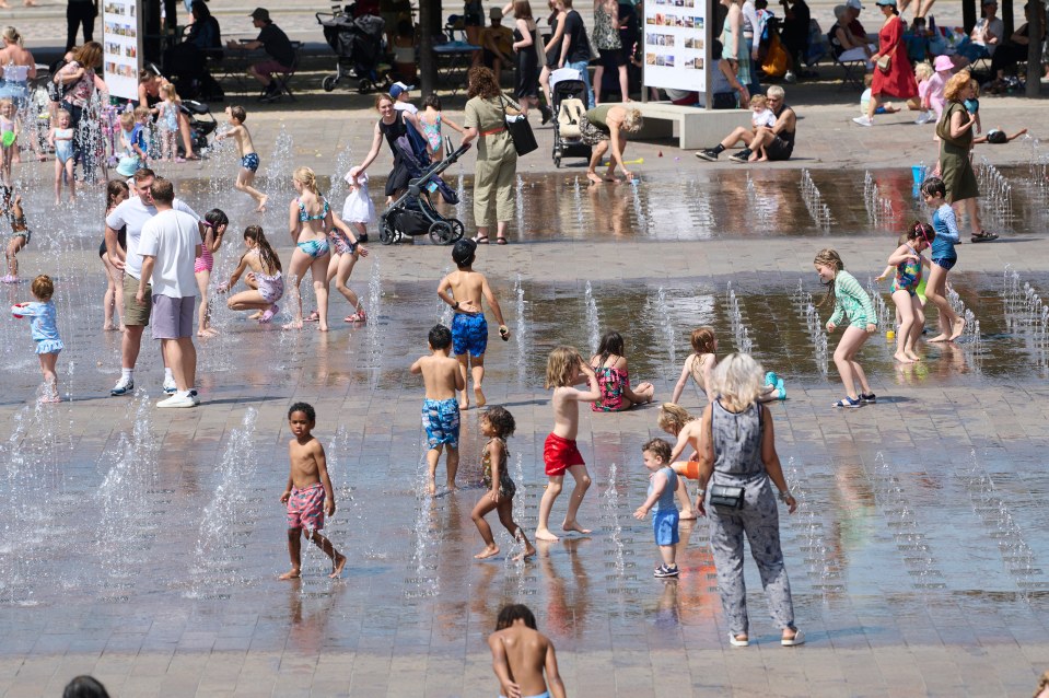 Families cool off in the fountains at Granary Square, behind Kings Cross Station