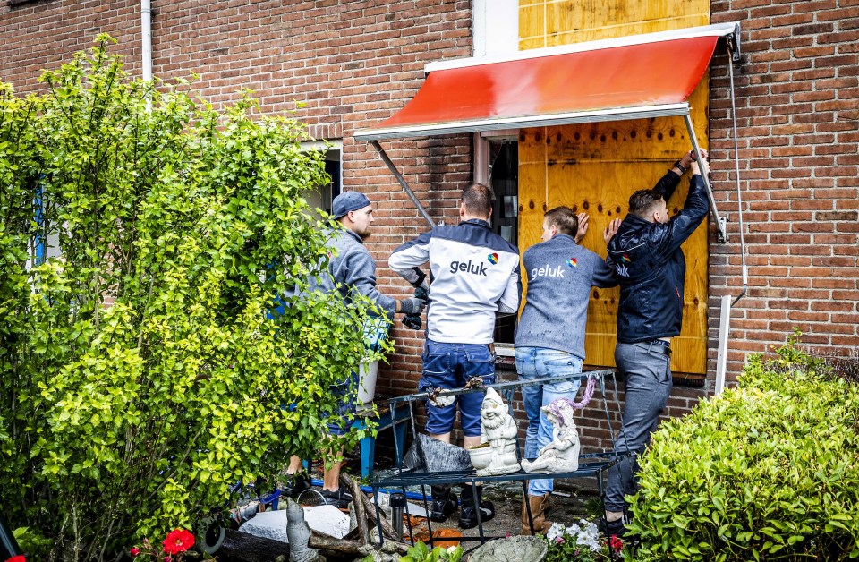 A home being boarded up as people inspect the damage caused by the tornado