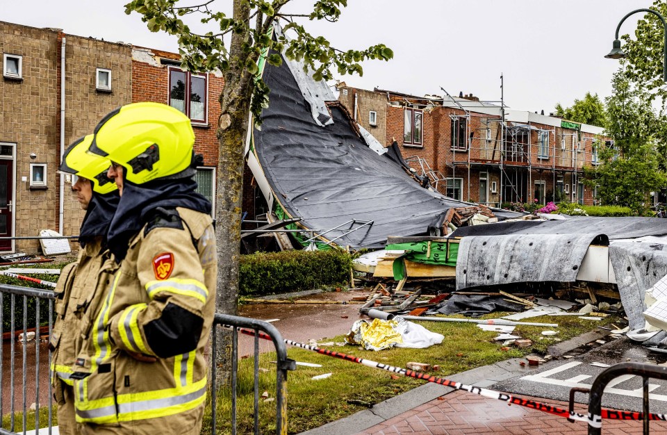 Emergency services personnel stand near a building damaged by a tornado in Zierikzee