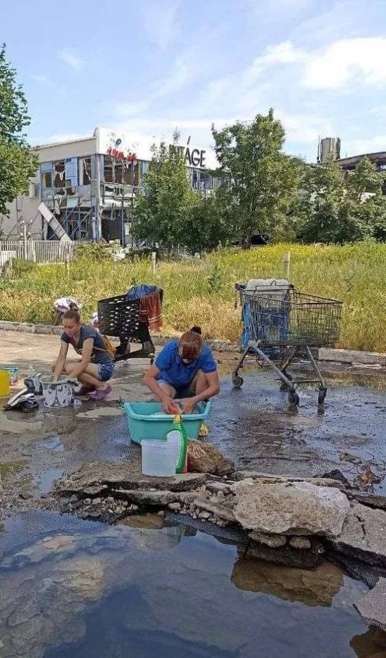 Mariupol residents wash their clothes in stagnant water on the street