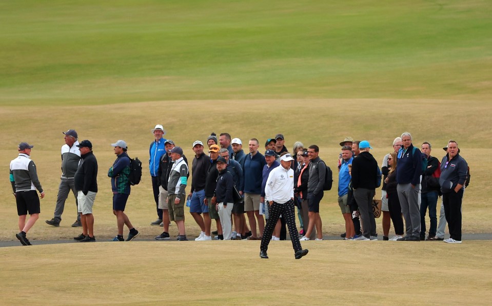 Poulter walks past a crowd on the first fairway after being booed before his opening tee shot