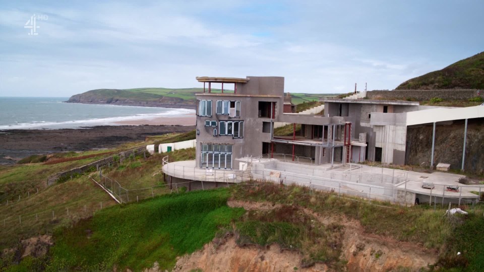 a large house is being built on a hill overlooking the ocean