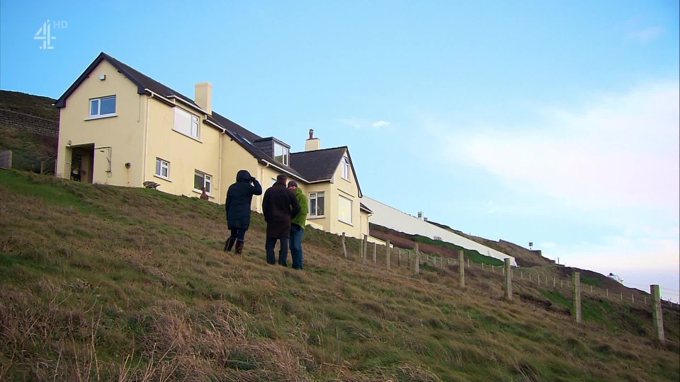 a group of people standing on a hill in front of a yellow house with the channel 4 logo