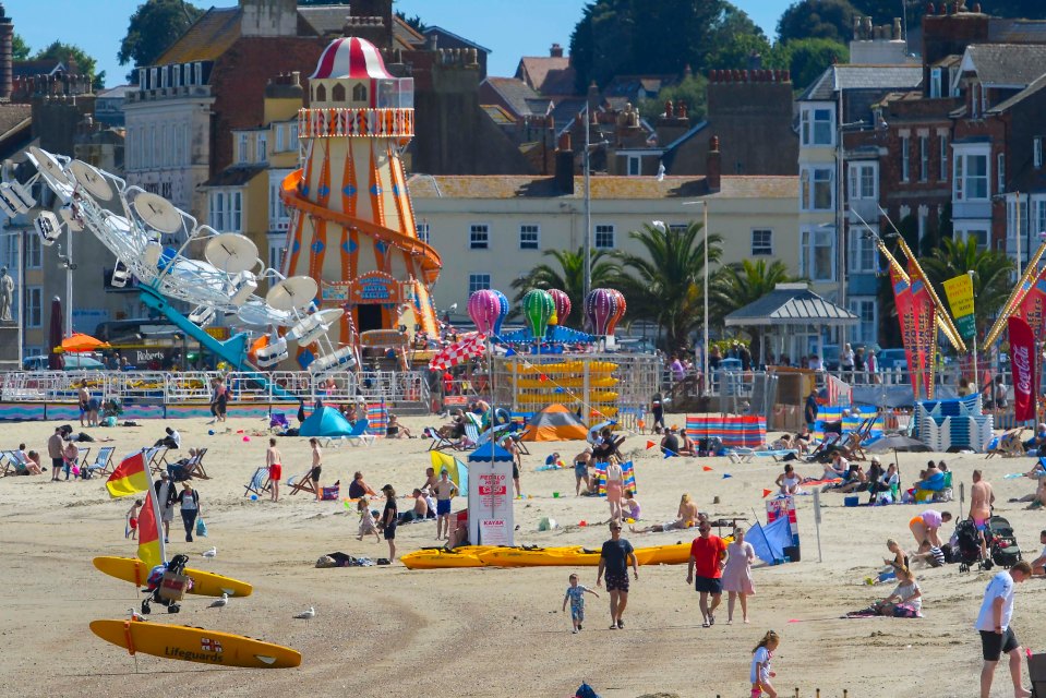 Families on the beach enjoying the hot afternoon sunshine at the seaside resort of Weymouth in Dorset