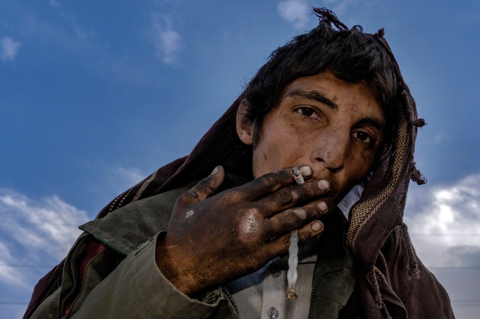 A drug addict smokes heroin on the edge of a hill in Kabul