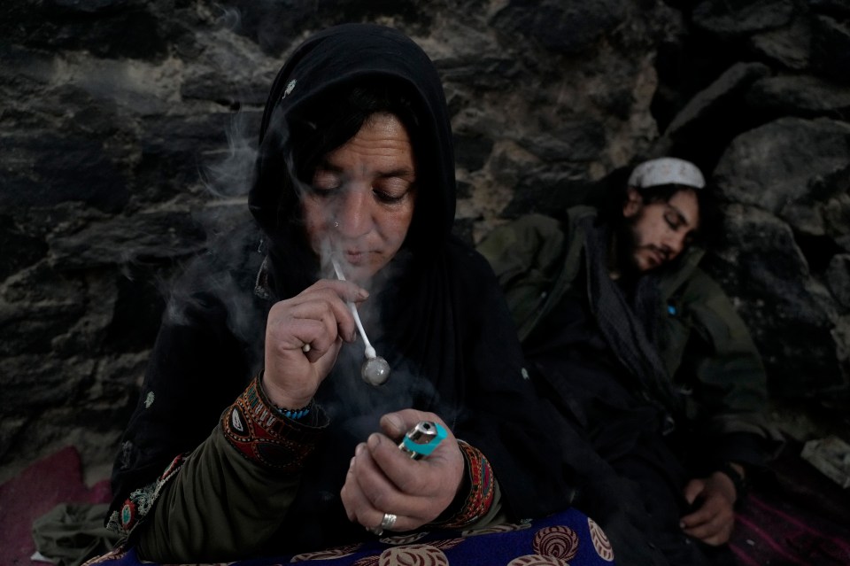 A drug addict smokes heroin on the edge of a hill in the city of Kabul