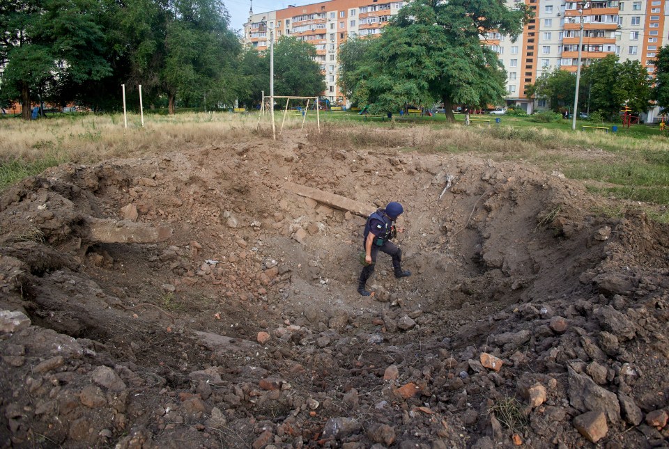 A policeman inspects a shell hole in Kharkiv, which has been ravaged by Russian attacks