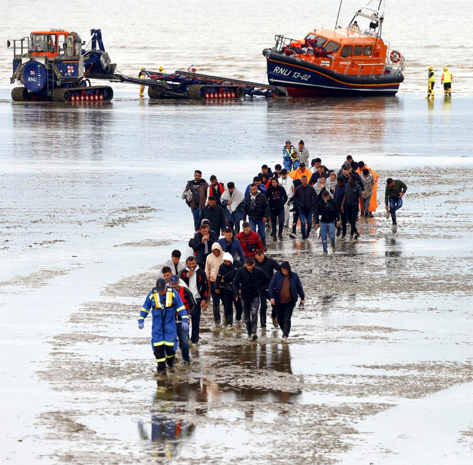 Migrants are helped ashore as a row brews over millions of pounds spent chartering boats to rescue them