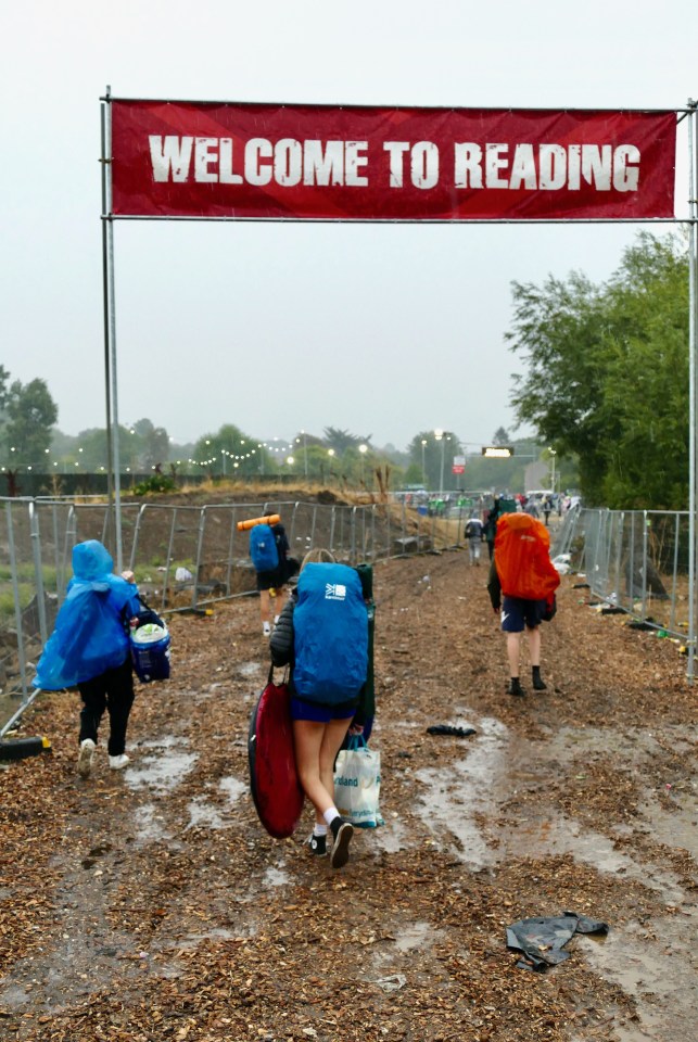 Soaked Reading Festival fans trudge through mud at the site after torrential rain fell