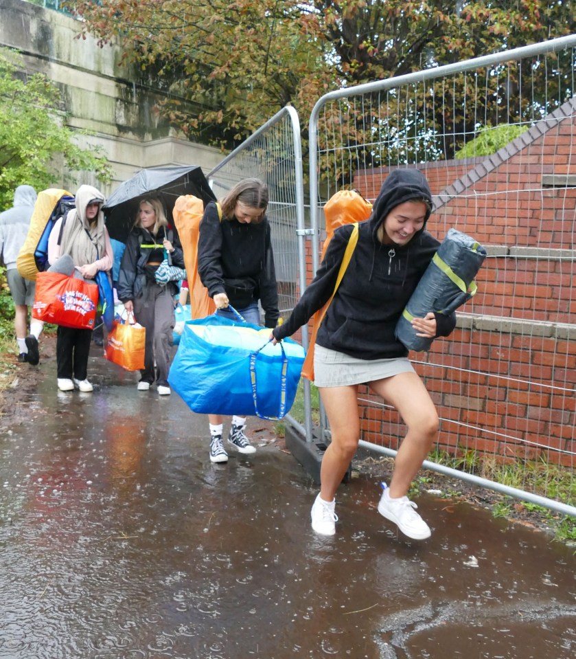 Reading Festival punters in Berkshire drag sodden bags and crates of beer through ankle deep water