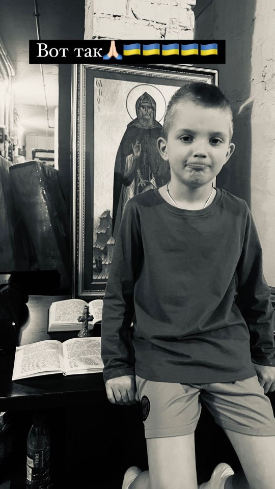 Black and white photo of a boy standing in front of a religious icon, praying for Ukraine.