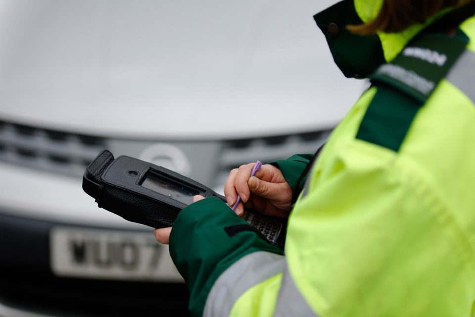 A parking warden issues a ticket