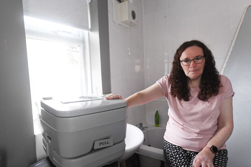 Helen with the portable toilet given to her to use until the problems are resolved