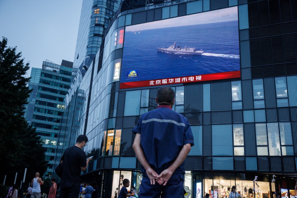 A man watches a Chinese state media broadcast about the massive war games near Taiwan