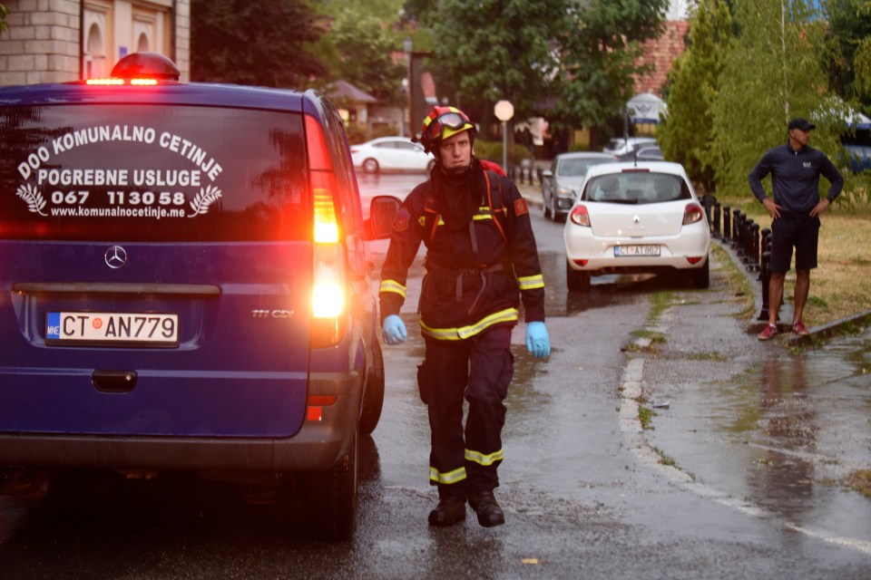 A firefighter walks by a hearse on the site of the attack in Cetinje