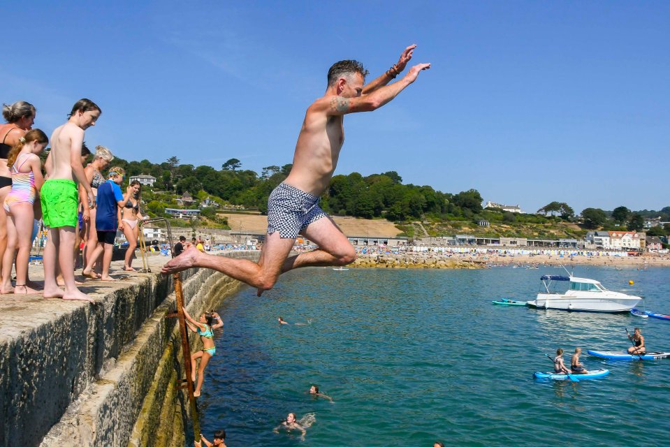 Daredevil swimmers leap off the Cobb Harbour wall at Lyme Regis, Dorset