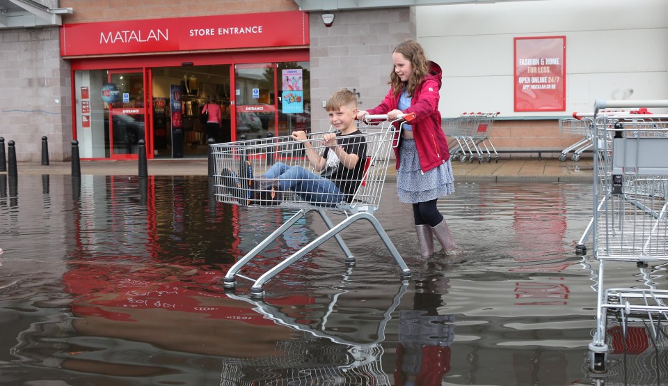 The rain came early north of the border with storms hitting parts of Scotland (pictured Darcie Bell pushing her brother Brogan in a trolley)