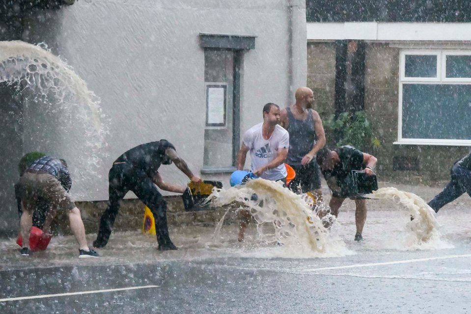 Locals desperately try to clear flash flood water from the Seagulls Restaurant in West Bay, Dorset during a downpour