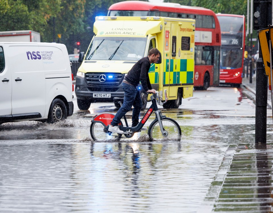 A cyclist struggles through heavy surface water on the Euston Road in central London