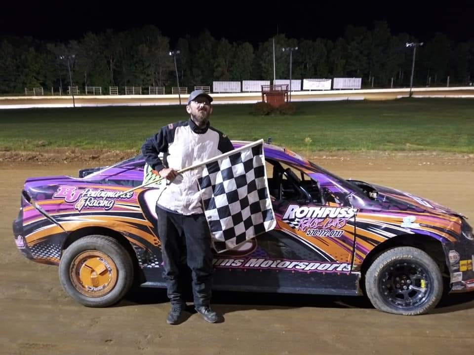 Robert posing in front of a race car