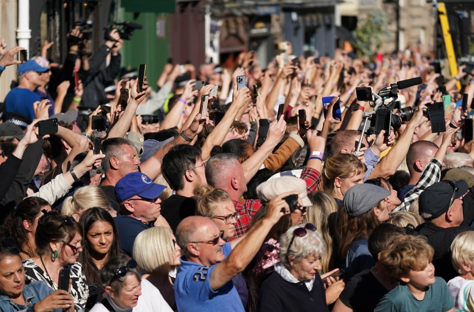 Crowds wave ahead of the coffin leaving the church