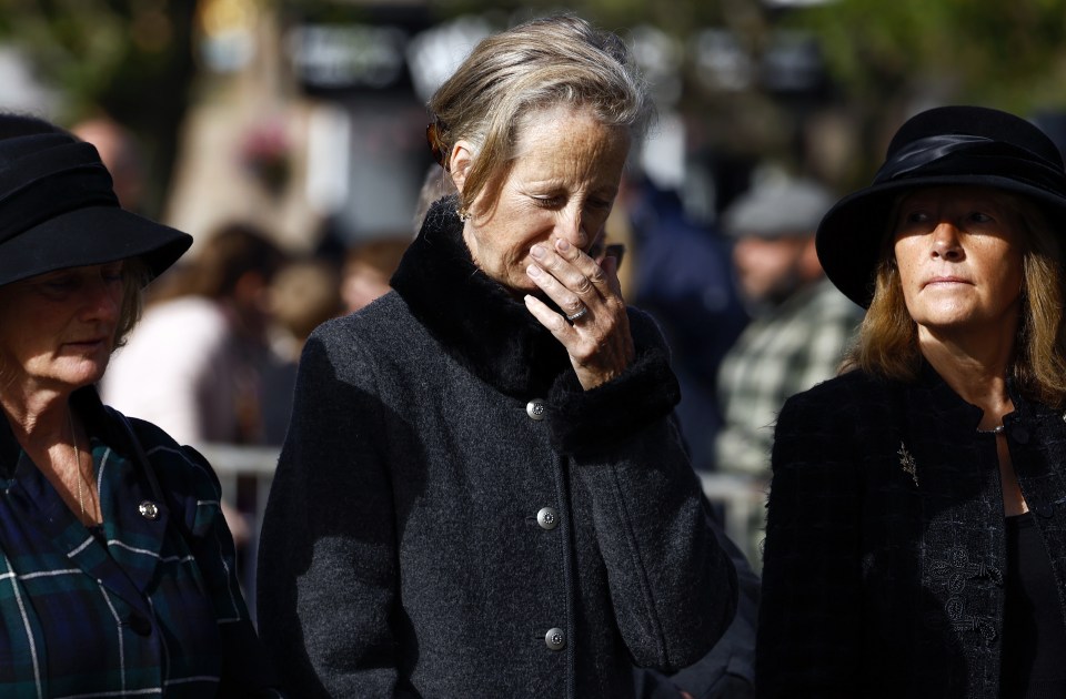 A woman looks emotional as people gather in tribute as the cortege carrying the coffin of the late Queen Elizabeth II passes through Ballater, Scotland, on Sunday