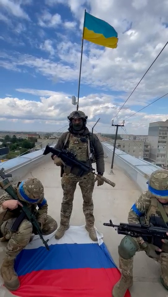 A Ukrainian soldier standing on Russian flag as his country’s one is raised