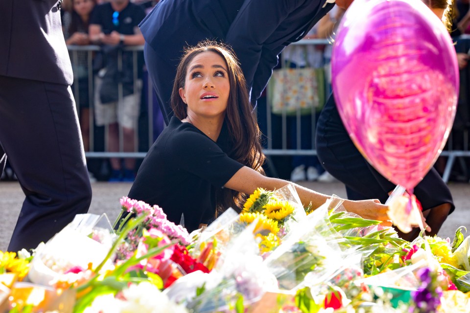 Meghan Markle looks at floral tributes laid on the Long Walk at Windsor