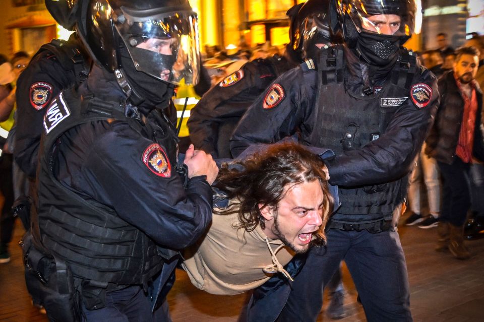 Police officers in Moscow detail a man during a demonstration