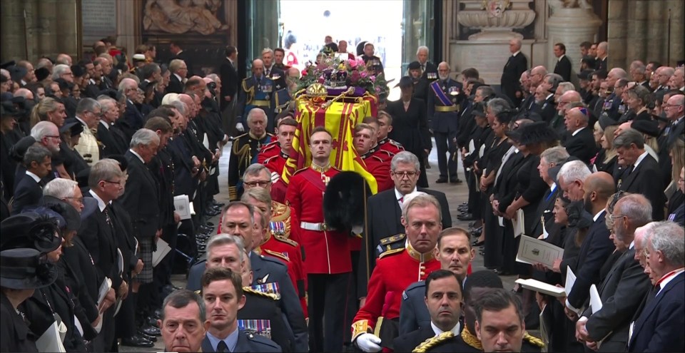 Mourners watch as the Queen is carried through Westminster Abbey