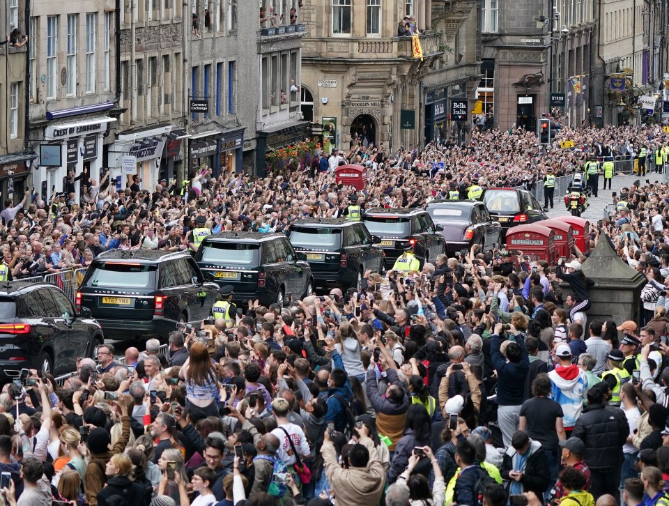 The crowd waits in silence as the procession passes